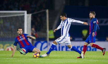 Sergio Busquets (izquierda) del FC Barcelona intenta parar el balón en posesión de Carlos Vela (centro) de la Real Sociedad.