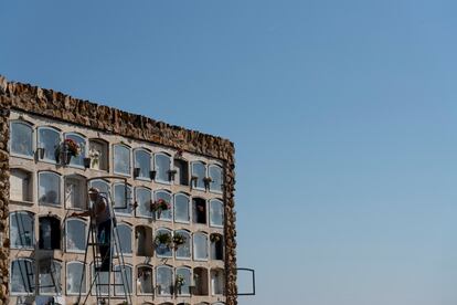 Un hombre subido a una escalera limpia un nicho en el cementerio de Montjuïc de Barcelona.

