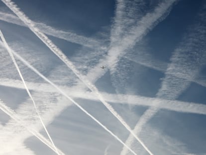 Un avión volando por un cielo lleno de estelas de vapor.