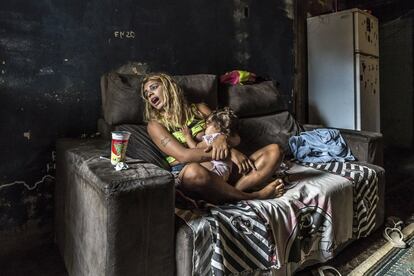 Pamela, de 16 años, con su hija de 17 meses. Vive con su madre en el antiguo edificio abandonado del Instituto Brasileño de Geografía y Estadísticas, un inmueble okupado por unas 100 familias en la favela Mangueira, en Río de Janeiro (Brasil). Unos dos millones de personas –aproximadamente el 30% de la población de Río (6,45 millones)– viven en favelas que a menudo carecen de las instalaciones sanitarias adecuadas, así como de colegios, condiciones de seguridad o asistencia médica.
