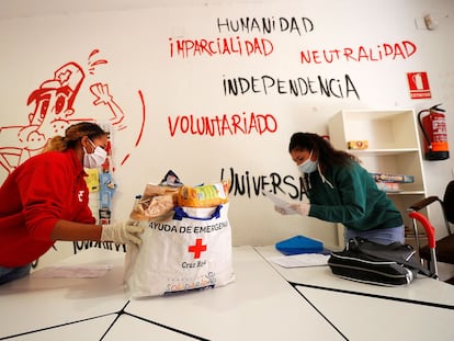 Una voluntaria de Cruz Roja entrega una bolsa con productos de primera necesidad a una joven en Valencia. / MANUEL BRUIQUE (Efe)