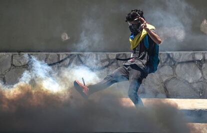 Un manifestante de la oposición patea un bote de gas lacrimógeno durante los enfrentamientos con la policía.