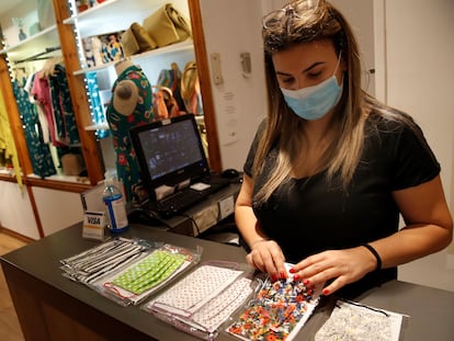 Una empleada de una tienda de Barcelona coloca unas mascarillas.