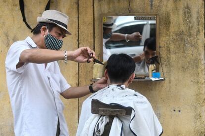 Un peluquero protegido con una mascarilla atiende a un cliente en la ciudad de Hanói (Vietnam), el 28 de febrero.