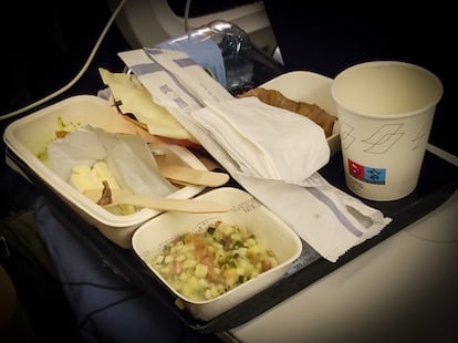 Una bandeja de comida, con restos de alimentos y envases, en un vuelo de largo alcance.