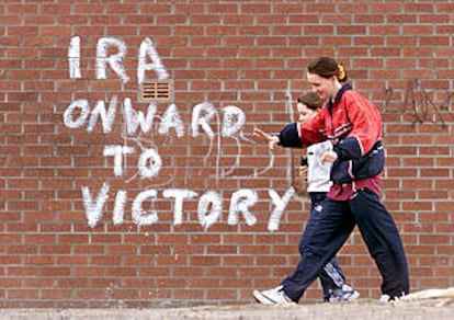 Dos muchachas de Belfast pasan junto a una pintada que dice &#39;El IRA, hacia la victoria&#39;.