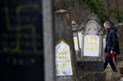 Un hombre pasa junto a las tumbas de un cementerio judío en Quatzenheim (Francia), pintadas con esvásticas nazis azules y amarillas.