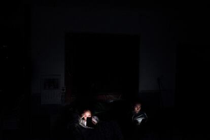 Aitana y Rocío iluminadas por sus teléfonos móviles en el porche de su casa al anochecer.  Su casa está ubicada en el sector 6. 