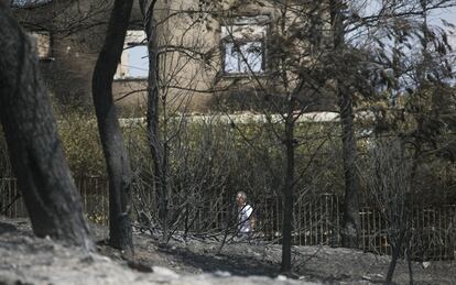 Un hombre camina por una zona afecta por el fuego de la localidad griega de Mati.