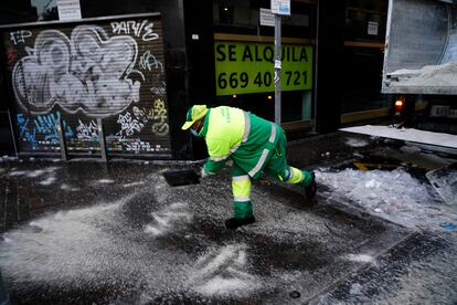 Un operario esparce sal en una acera de la calle Bravo Murillo