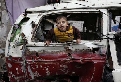 Un niño palestino juega dentro de los restos de un coche destrozado durante el conflicto entre Israel y Gaza.