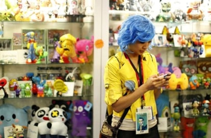 Una mujer disfrazada envia un mensaje de texto desde su móvil en una tienda de juguetes en la Comic Con, en San Diego (EE UU)