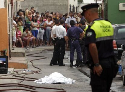 Vecinos observan el cadáver de la mujer tendido en la calle, después de ser sofocado el incendio.