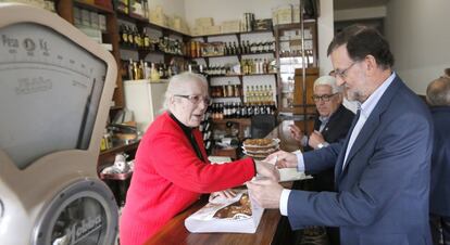 El presidente del Gobierno en funciones, Mariano Rajoy, recibe una tarta que le regala la dueña de una tienda en agradecimiento por su visita, durante un paseo por Vilalba (Lugo), localidad natal del fundador del PP, Manuel Fraga, dentro de la campaña electoral para las elecciones gallegas.