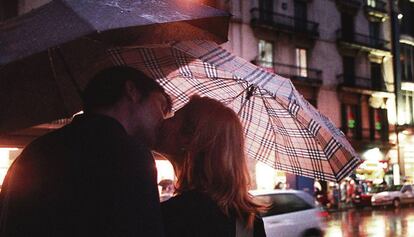 Una parella troba aixopluc i moixaines, amb tendresa, sota els paraigües.