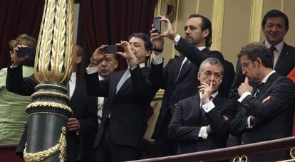 El presidente de la Xunta, Alberto Núñez Feijóo, y el lehendakari, Iñigo Urkullu, hablan en la tribuna de invitados del Congreso mientras el expresidente de la Comunidad de Madrid, Ignacio González, saca una fotografía.