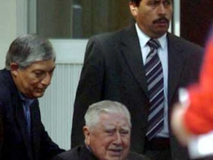 Augusto Pinochet, ayudado por sus guardaespaldas en 2004.