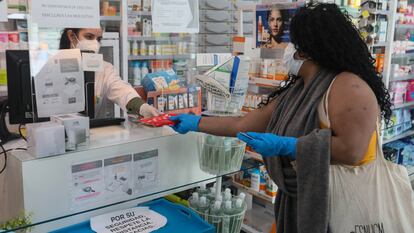 Un farmacéutico entrega a un cliente una de las mascarillas en una farmacia de Madrid.