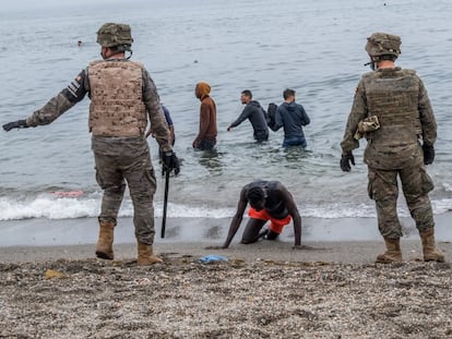 Soldados españoles junto a inmigrantes que han cruzado a nado por la frontera del Tarajal, en Ceuta, este martes.