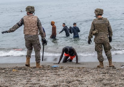 Un hombre arrodillado en una playa de Ceuta mientras el Ejército acordona la zona, el pasado martes.