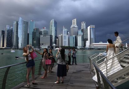 Unos turistas se hacen fotos en el puerto deportivo Marina Bay con los edificios del distrito financiero de fondo.