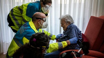 Un equipo sanitario de la UVI atiende a una anciana en su casa de Madrid.
