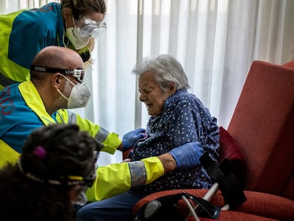 Un equipo sanitario de la UVI atiende a una anciana en su casa de Madrid.