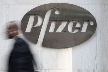 Un hombre pasa ante un cartel de Pfizer colgado en la entrada de la sede principal de la farmac&eacute;utica en Nueva York.