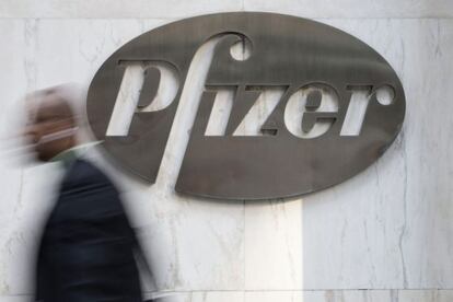 Un hombre pasa ante un cartel de Pfizer colgado en la entrada de la sede principal de la farmacéutica en Nueva York.