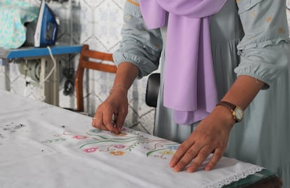 Una mujer marroquí añade cuentas brillantes al mantel que otras compañeras del taller han pintado a mano.