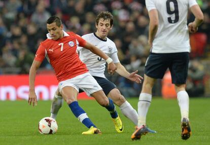 Alexis, autor de los dos goles de Chile, intenta llevarse el balón ante Baines.