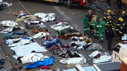 Bomberos y personal de rescate observan los cuerpos de las víctimas del suceso en el centro de Johannesburgo, este jueves.