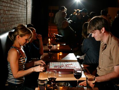 A couple plays Scrabble while sipping wine in a Los Angeles bar.