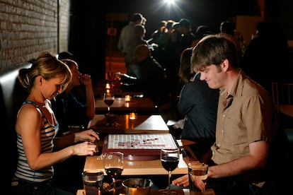 A couple plays Scrabble while sipping wine in a Los Angeles bar.