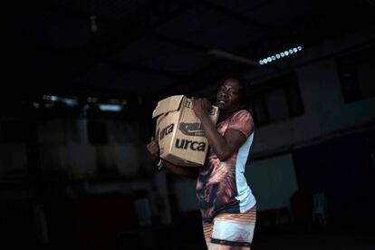 Una mujer carga una caja de alimentos de donación en una favela de Río de Janeiro, este martes.