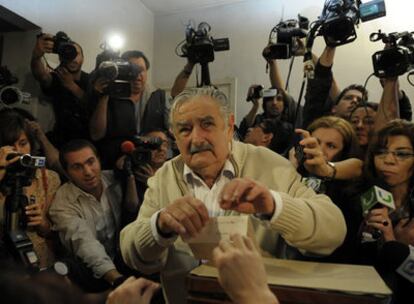 El candidato del Frente Amplio, José Mujica, deposita su voto rodeado de periodistas en Montevideo.
