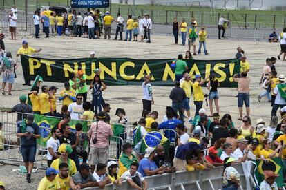 Apoiadores de Bolsonaro com o cartaz "PT nunca mais" aguardam cerimônia na Praça dos Três Poderes.