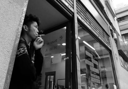 Un comerciante fuma a la puerta de su establecimiento en Madrid.