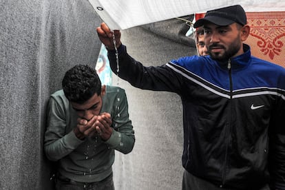 Un hombre bebe agua acumulada en un toldo que protege una tienda de campaña, en un campamento de la agencia de la ONU para los refugiados palestinos, UNRWA, en Rafah, este martes. 