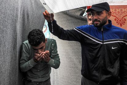 Un hombre bebe agua acumulada en un toldo que protege una tienda de campaña, en un campamento de la agencia de la ONU para los refugiados palestinos, UNRWA, en Rafah, este martes.
