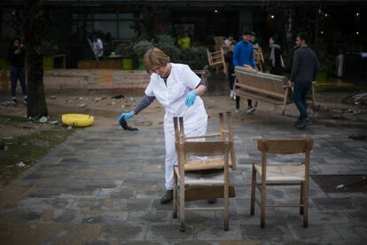 Una dona neteja el mobiliari d'un restaurant a la platja de Sant Sebastià, a Barcelona.
