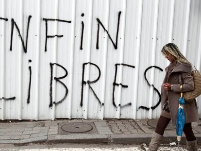 Una mujer camina ante una valla de Túnez capital en la que se lee una pintada en francés: "Al fin libres".