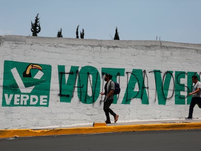 Peatones frente a una barda pintada con el logo del Partido Verde, antes de las elecciones de junio 2021, en Ciudad de México.