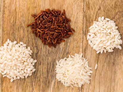 Four different kinds of rice on a wooden board: Carnaroli rice (Italy), Camargue red rice (France), Basmati long grain rice (India) and Bomba rice (Spain)