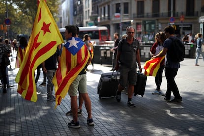 Jóvenes con esteladas rodeadas de turista en Plaza Catalunya, en Barcelona.