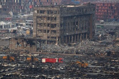 Miembros de los servicios de rescate trabajan entre cientos de vehículos quemados y varios edificios destruídos tras varias explosiones en Tianjin (China).