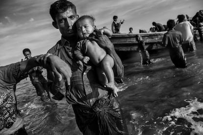 Un refugiado rohingya lleva un bebé en brazos después de llegar en barco a la orilla bangladesí del río Naf, en Shah Porir Dwip, después de huir de su aldea en Myanmar, el 1 de octubre de 2017.  Desde las redadas de agosto, el pequeño grupo insurgente ha lanzado pocos ataques hasta este viernes, cuando sus combatientes tendieron una emboscada a un camión del Ejército birmano, hiriendo a varios miembros de las fuerzas de seguridad.