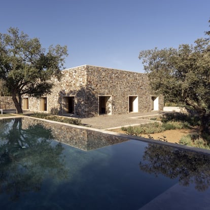 La casa domina con discrección el lugar, recostándose en la ladera natural junto a las hermosas encinas existentes y abriendo los ojos sobre el paisaje y la ciudad de Cáceres. Desde esta posición dominante la casa trata de ser respetuosa con el entorno natural-artificial, estableciendo vínculos formales y constructivos con el entorno próximo y el casco histórico de la ciudad. La casa se presenta como un sencillo volumen prismático de planta cuadrada, de 16 metros de lado, construida con muros de piedra cuarcita cacereña. En cada uno de los lados se disponen tres huecos de ventana, de dos metros diez centímetros, enmarcados con piedra de granito extremeño de tono cálido.