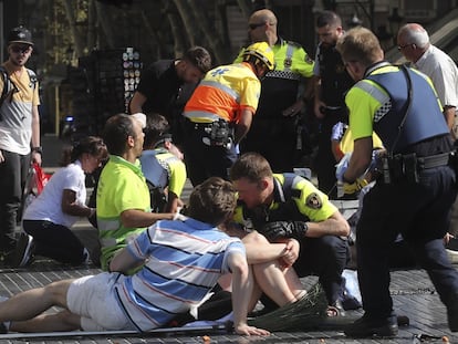 Agentes de policía, sanitarios y transeúntes atienden a los heridos en el atentado terrorista yihadista de La Rambla de Barcelona en 2017.