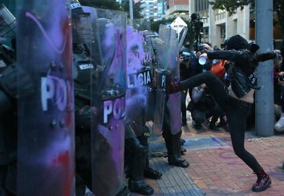 Una manifestante patea el escudo de un uniformado durante una protesta contra la brutalidad policial en Bogotá.